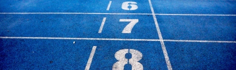 A set of numbers, with 8 at the forground going back to 2, in white, painted on blue pavement.